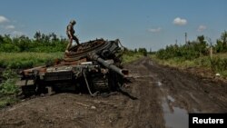 Украинский военный осматривает разбитый российский танк в Новодаровке, Запорожская область