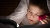 Kid boy with reading a book with his flashlight in his bedroom at night